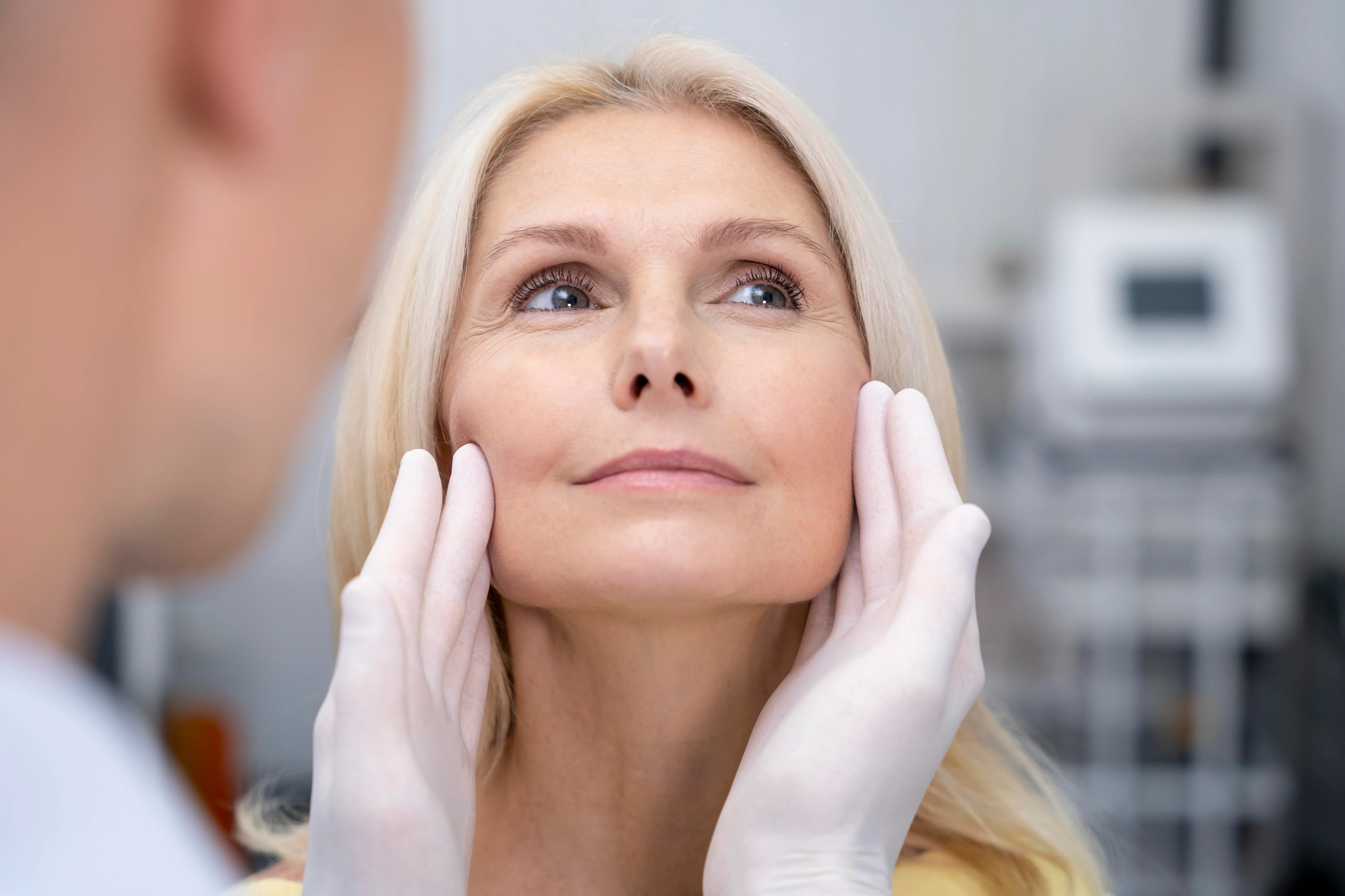 Close up of doctor inspecting womens face prior to skin tightening
